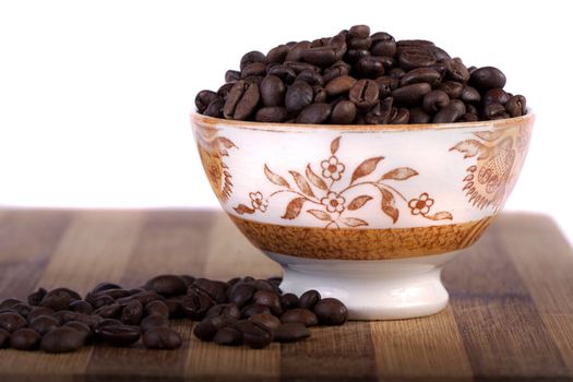 Close view of a bunch of roasted beans of coffee inside a bowl.