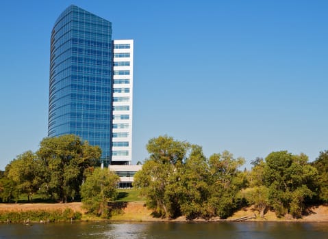 Modern blue and white building on tree lined river