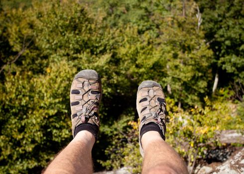 Hiker looks over valley in the Shenandoah on a climb of Old Rag with feet hanging on the edge