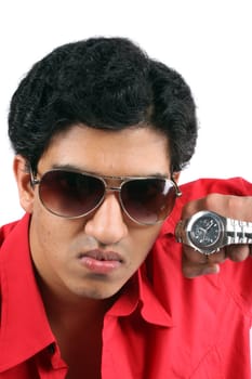 A portrait of a young Indian guy aggresively showing time on his watch.