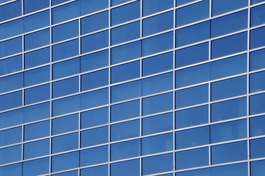 Exterior windows of a modern commercial office building reflecting blue sky