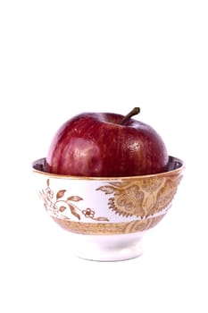 Close up view of a single red apple on a bowl isolated on a white background.