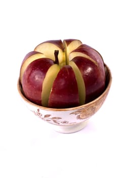 Close up view of a single red apple sliced inside a bowl isolated on a white background.