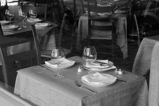 Black and white view of an empty restaurant dining room looking from the outside