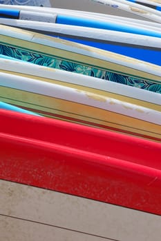 A row of brightly colored renal surfboards laying on the sand in Hawaii