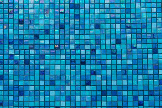 Bright blue glass tiles lining the bottom of a swimming pool