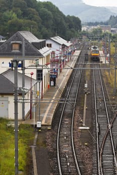 Small railwaystation with railway or railroad and train in the hills