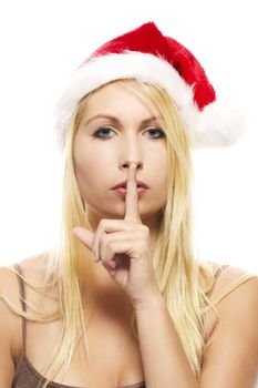 beautiful blonde woman wearing santa's hat putting finger on mouth to shhht on white background