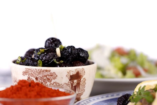 Close up view of a some tempered dry black olives and a salad.