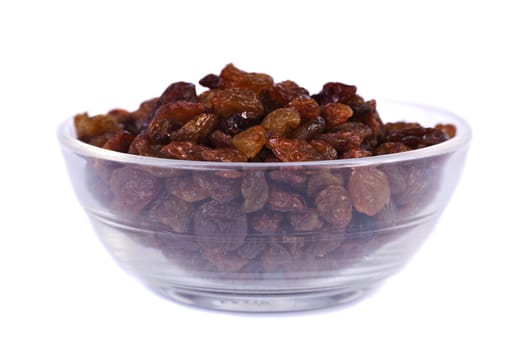 Close view of a pile of dry raisins on a bowl isolated on a white background.