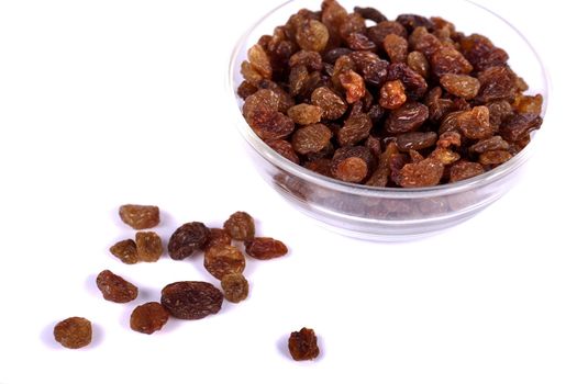 Close view of a pile of dry raisins on a bowl isolated on a white background.