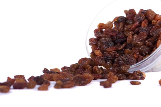 Close view of a pile of dry raisins on a bowl isolated on a white background.