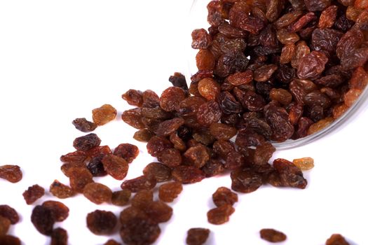 Close view of a pile of dry raisins on a bowl isolated on a white background.