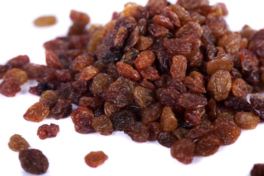 Close view of a pile of dry raisins isolated on a white background.