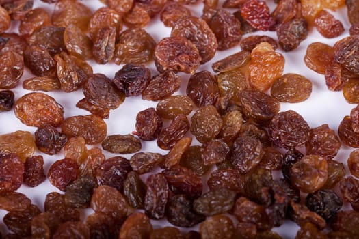 Close view of a pile of dry raisins isolated on a white background.