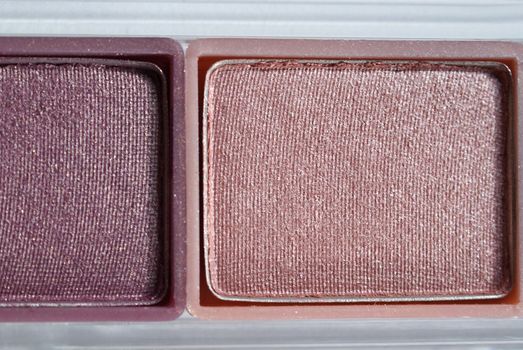 A closeup of an eyeshadow palette - plum and pink. 