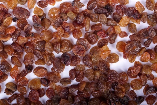 Close view of a pile of dry raisins isolated on a white background.