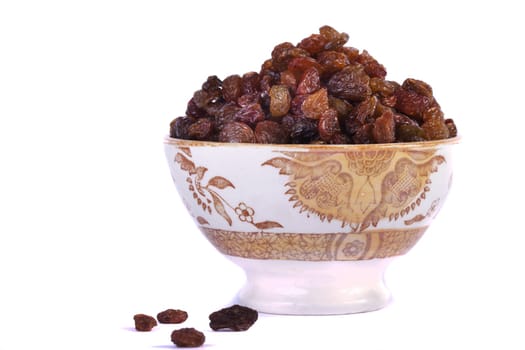 Close view of a bowl filled with dry raisins isolated on a white background.