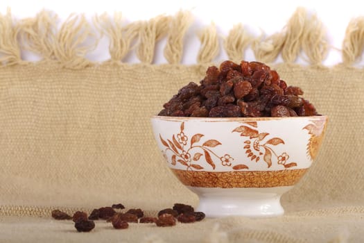 Close view of a bowl filled with dry raisins isolated on a white background.