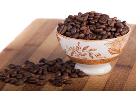 Close view of a bunch of roasted beans of coffee inside a bowl.