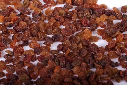 Close view of a pile of dry raisins isolated on a white background.