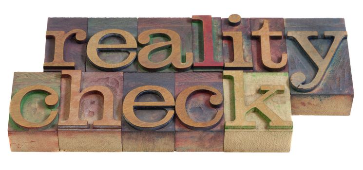 reality check concept  - words in  vintage wooden letterpress printing blocks, stained by color inks, isolated on white