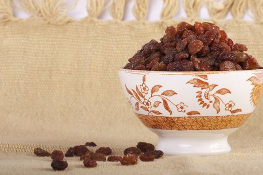 Close view of a bowl filled with dry raisins isolated on a white background.