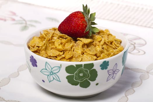 View of a bowl of cereals with strawberry on top.