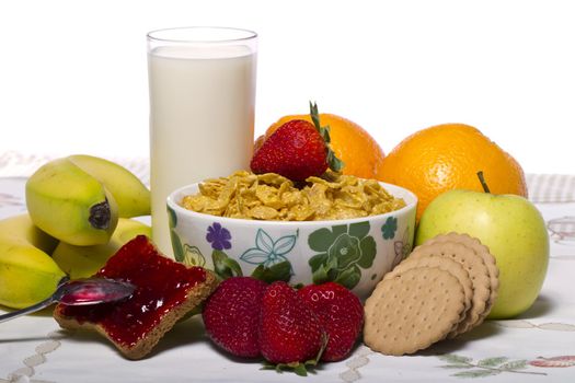 View of a bowl of cereals surrounded by fruit and milk.