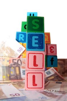 toy letters that spell sell against a cash background