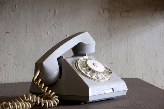 Old gray phone on the wooden desk