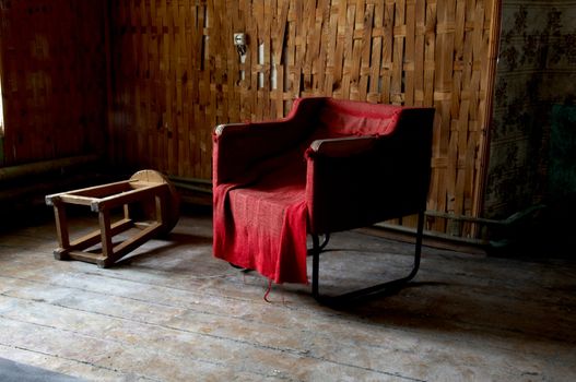 Old red armchair with the plywood wall