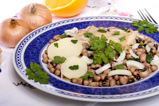 View of a meal with brown beans with cod and potatoes, tempered with olive oil and parsley.