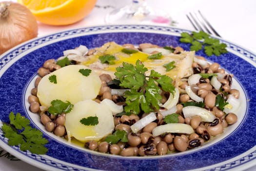 View of a meal with brown beans with cod and potatoes, tempered with olive oil and parsley.