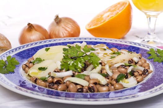 View of a meal with brown beans with cod and potatoes, tempered with olive oil and parsley.