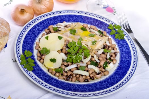 View of a meal with brown beans with cod and potatoes, tempered with olive oil and parsley.