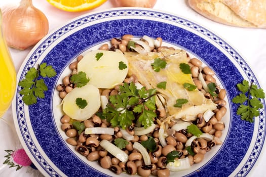 View of a meal with brown beans with cod and potatoes, tempered with olive oil and parsley.