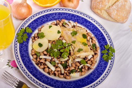 View of a meal with brown beans with cod and potatoes, tempered with olive oil and parsley.