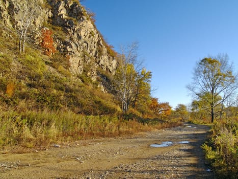 Autumn sunny day on road at a mountain slope