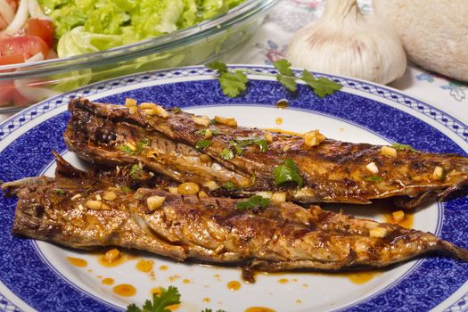 Close up view of a Portuguese meal of Wahoo grilled fish with annatto sauce and Mediterranean salad.  