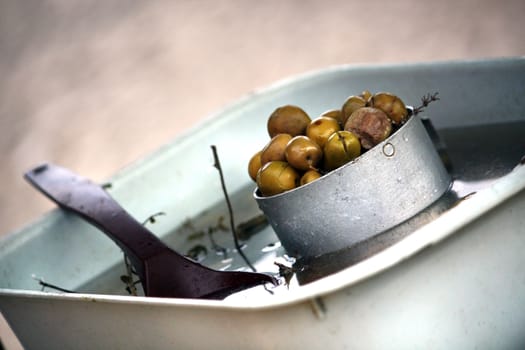 View of a container full of green olives and a spoon.