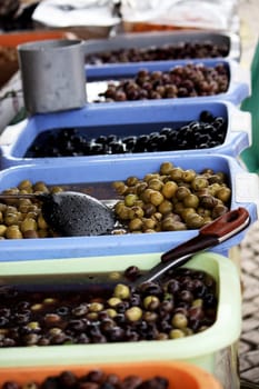 View of many buckets filled with many kind of olives, including greens, blacks and browns on a market.
