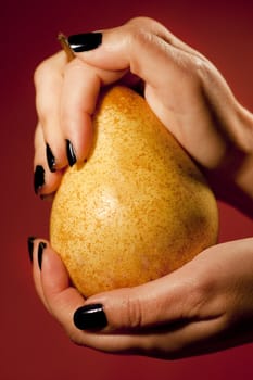 Close up view of two woman hands holding a pear.
