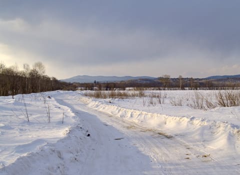 Winter landscape with cloudy day on a country road