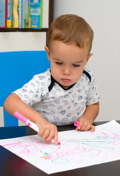 Serious little boy draws a marker
