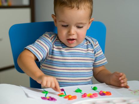 Little boy and flowers of colored plasticine