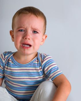 Cute crying boy on gray background