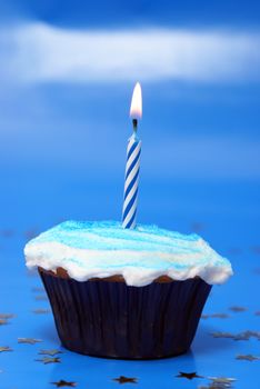 A lit candle inserted in a frosted cupcake for someone to make that special wish they want to come true.