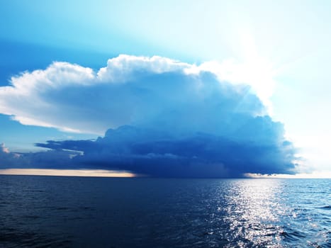 Bright blue sky with stormy clouds over a calm sea
