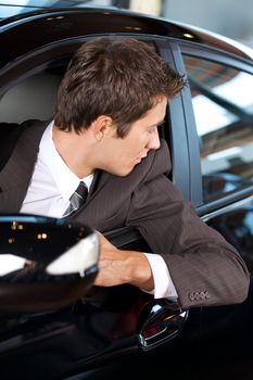 Young man sitting in new car